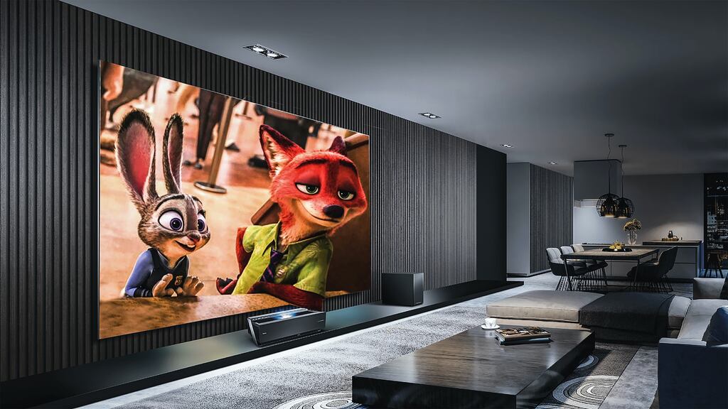 TV exibindo o filme Zootopia (raposa e lebre) na parede de um flat moderno. A imagem da TV é bonita, com cores vívidas, ilustrando um dos tipos de paineis LCD.